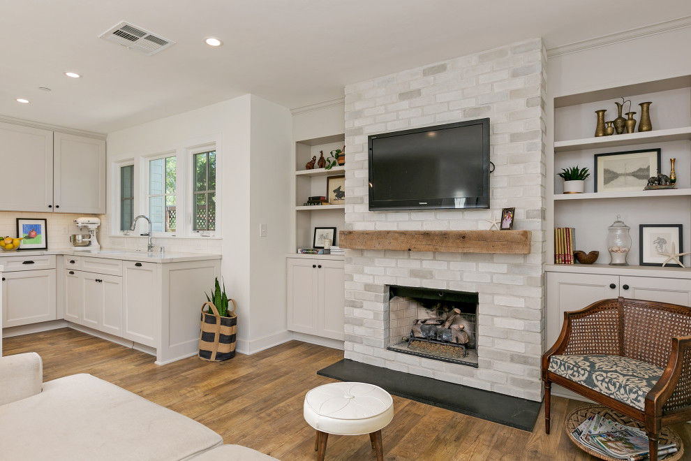 Design ideas for a mid-sized country open concept living room in San Diego with white walls, vinyl floors, a standard fireplace, a brick fireplace surround, a wall-mounted tv, brown floor and brick walls.