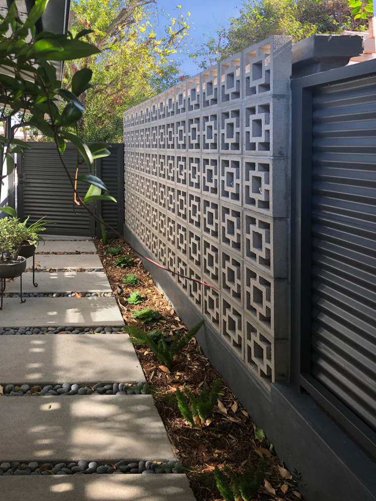 Inspiration for a medium sized retro front driveway partial sun garden for winter in Los Angeles with a garden path, concrete paving and a metal fence.