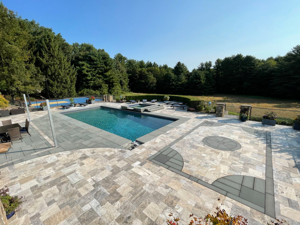 Large contemporary back rectangular lengths swimming pool in Boston with with pool landscaping and natural stone paving.