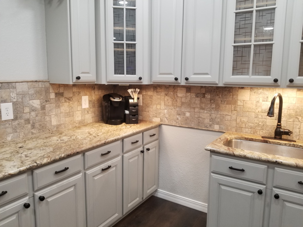 Inspiration for a mid-sized traditional u-shaped separate kitchen in Denver with an undermount sink, beaded inset cabinets, grey cabinets, granite benchtops, beige splashback, travertine splashback, stainless steel appliances, laminate floors, no island, brown floor and beige benchtop.