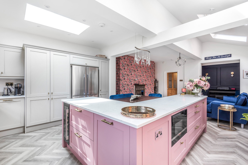 Mid-sized eclectic l-shaped eat-in kitchen in Berkshire with a single-bowl sink, shaker cabinets, pink cabinets, quartzite benchtops, white splashback, panelled appliances, with island and white benchtop.