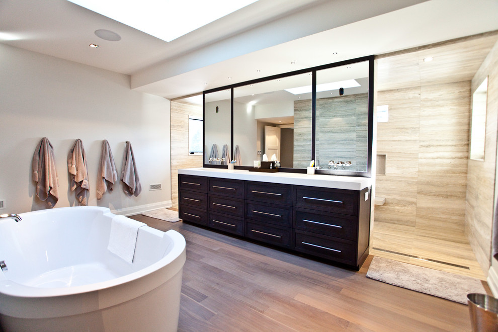 Photo of a large contemporary master bathroom in Toronto with shaker cabinets, dark wood cabinets, a freestanding tub, a curbless shower, grey walls, light hardwood floors and an undermount sink.