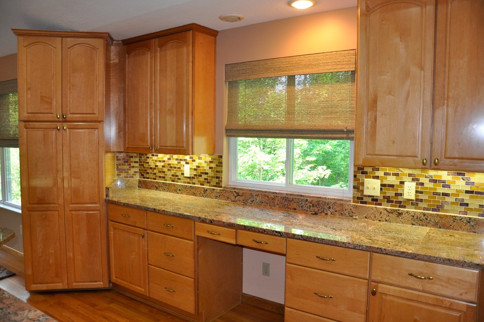 Eat-in kitchen - mid-sized transitional single-wall medium tone wood floor eat-in kitchen idea in Cincinnati with raised-panel cabinets, medium tone wood cabinets, granite countertops, multicolored backsplash, glass sheet backsplash and no island