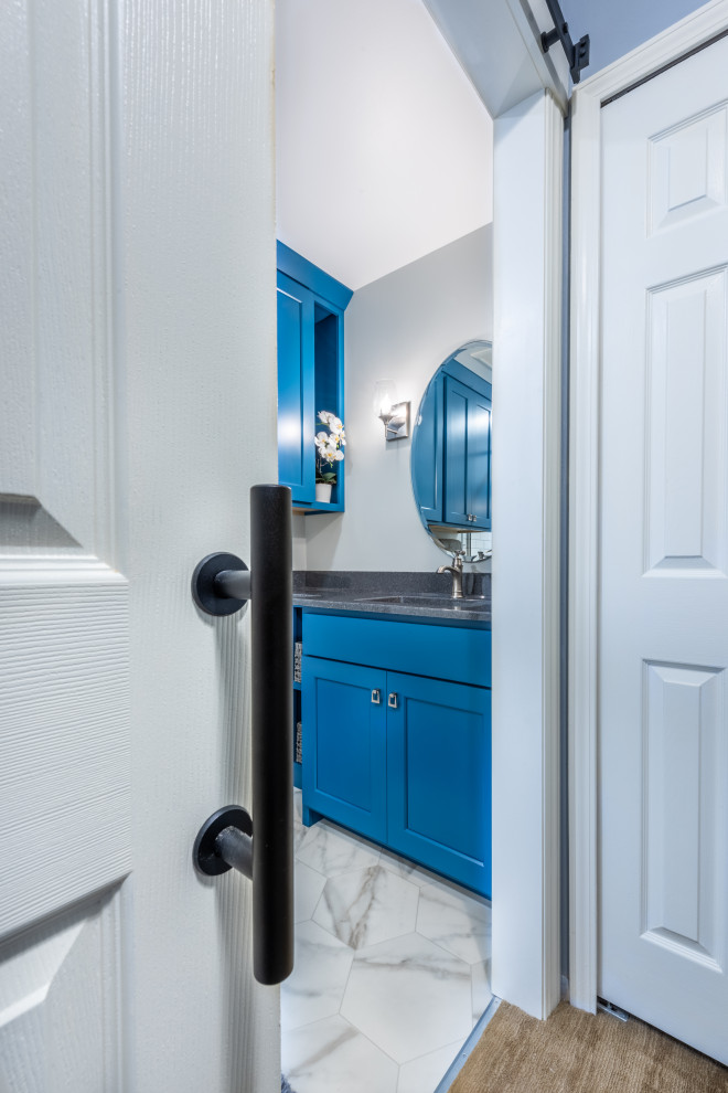 Пример оригинального дизайна: маленькая ванная комната в стиле неоклассика (современная классика) с синими фасадами, душем в нише, раздельным унитазом, белой плиткой, плиткой кабанчик, серыми стенами, полом из винила, душевой кабиной, монолитной раковиной, столешницей из оникса, белым полом, душем с раздвижными дверями, серой столешницей, тумбой под одну раковину и встроенной тумбой для на участке и в саду
