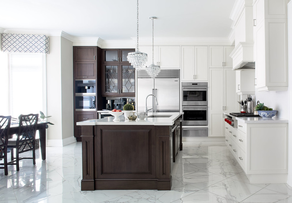 Large transitional l-shaped kitchen in Toronto with an undermount sink, recessed-panel cabinets, white cabinets, quartz benchtops, stainless steel appliances, porcelain floors, with island, white splashback, grey floor and white benchtop.