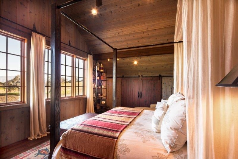This is an example of a large country master bedroom in Santa Barbara with dark hardwood floors.
