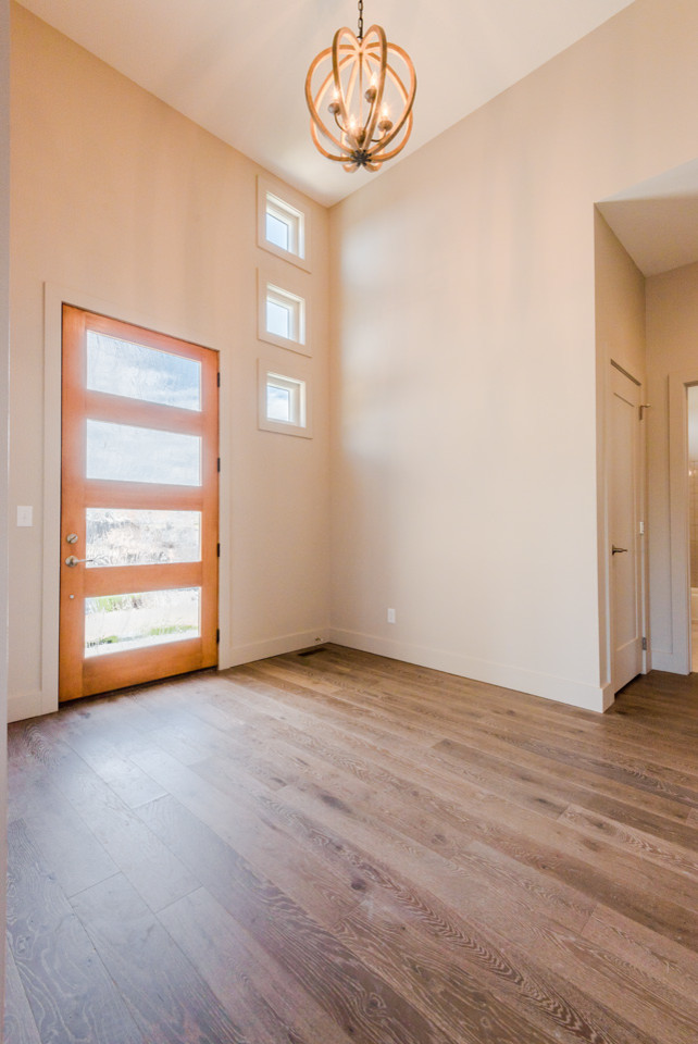 Large transitional dark wood floor home design photo with gray walls and a light wood front door