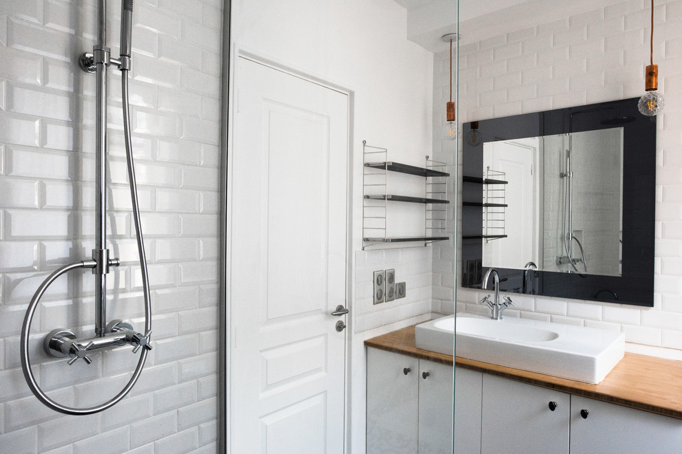 Inspiration for a small modern master bathroom in Paris with beaded inset cabinets, white cabinets, an undermount tub, an open shower, a wall-mount toilet, white tile, matchstick tile, white walls, cement tiles, a trough sink, wood benchtops, black floor and an open shower.