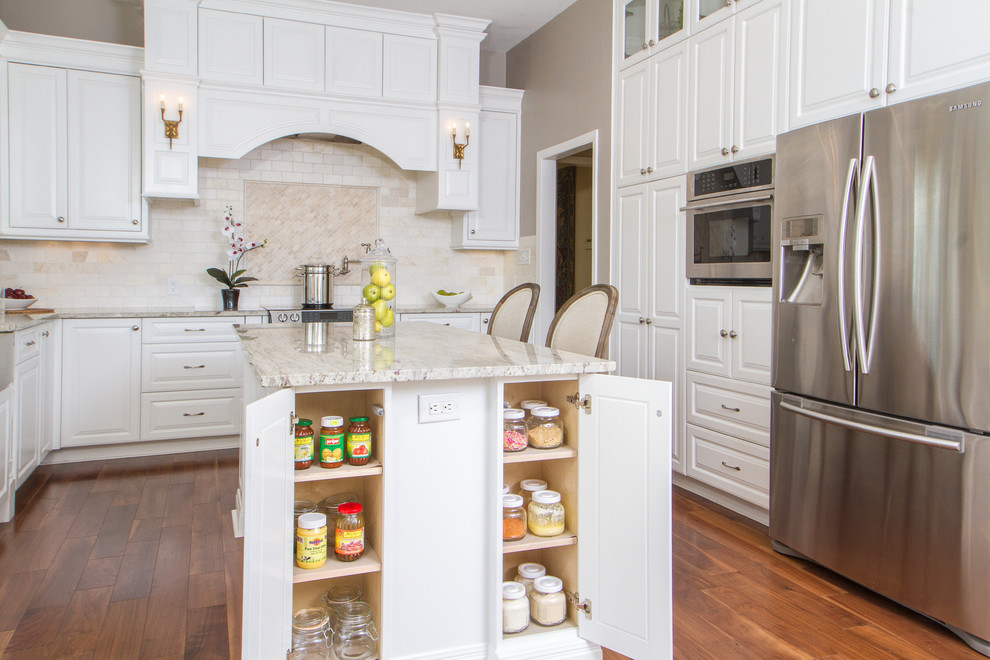 Eat-in kitchen - large transitional l-shaped medium tone wood floor eat-in kitchen idea in Austin with a farmhouse sink, raised-panel cabinets, white cabinets, granite countertops, beige backsplash, ceramic backsplash, stainless steel appliances and an island
