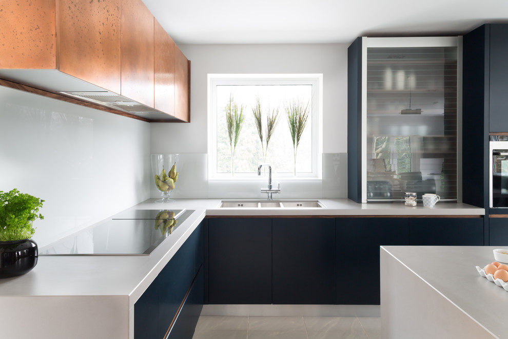 This is an example of a mid-sized contemporary eat-in kitchen in London with flat-panel cabinets, blue cabinets, quartzite benchtops, white splashback, panelled appliances, with island and a triple-bowl sink.