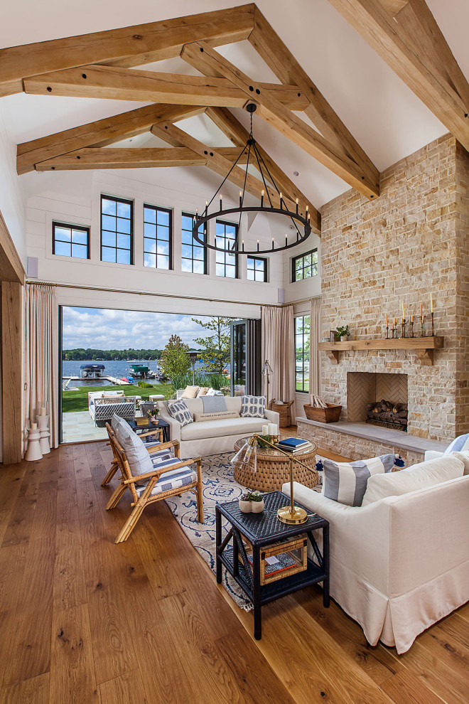 Ejemplo de sala de estar costera grande con suelo de madera en tonos medios y vigas vistas