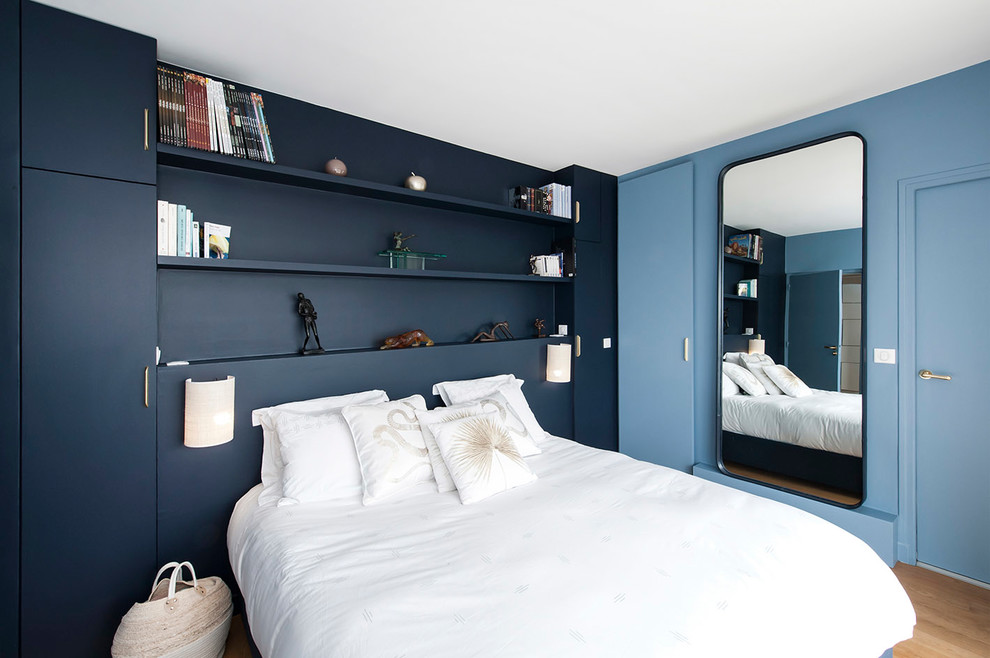 This is an example of a mid-sized contemporary master bedroom in Paris with blue walls, light hardwood floors, no fireplace and beige floor.