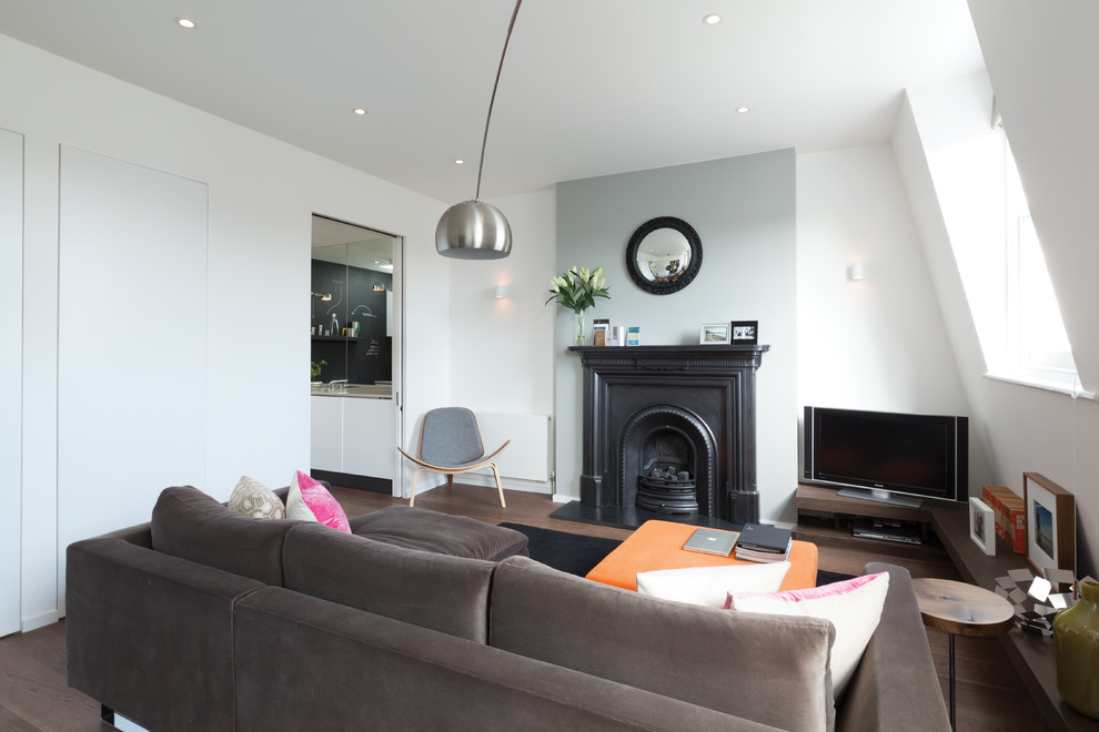 Photo of a small contemporary living room in London with white walls, medium hardwood floors, a standard fireplace, a stone fireplace surround and a freestanding tv.