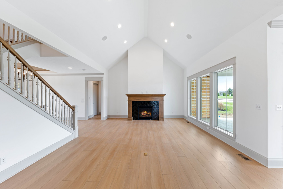 Inspiration for a large traditional open plan living room in Indianapolis with white walls, vinyl flooring, a standard fireplace, a tiled fireplace surround and beige floors.