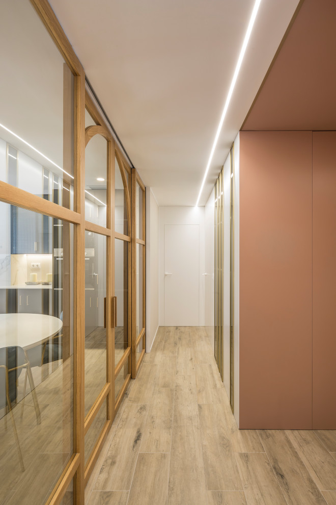 Idée de décoration pour un petit couloir avec un mur orange, un sol en bois brun et un sol marron.