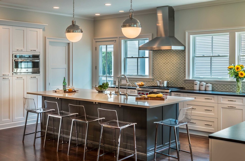 Photo of a transitional l-shaped open plan kitchen in Chicago with shaker cabinets, white cabinets, grey splashback, with island, a farmhouse sink, cement tile splashback, stainless steel appliances and medium hardwood floors.