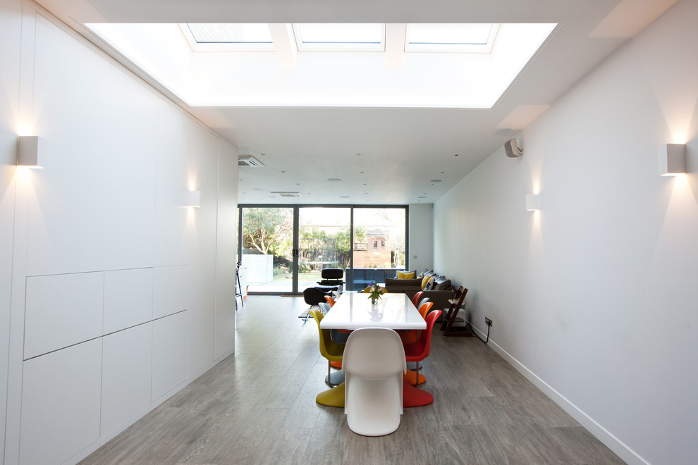Inspiration for a large contemporary open plan dining in London with white walls and light hardwood floors.