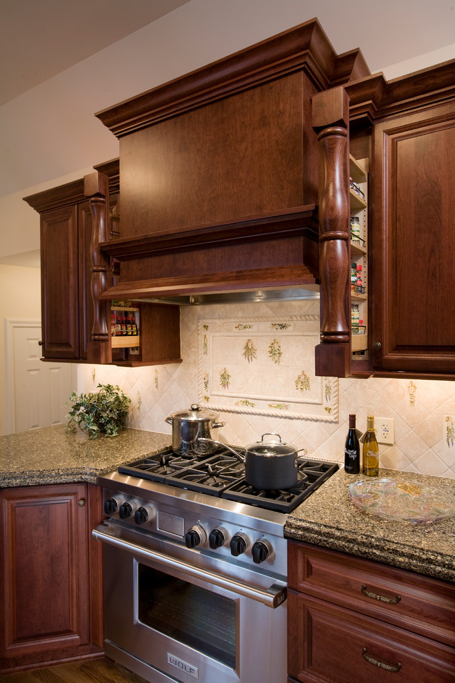 This is an example of a traditional galley eat-in kitchen in Chicago with an undermount sink, raised-panel cabinets, dark wood cabinets, quartz benchtops, beige splashback, stone tile splashback and stainless steel appliances.