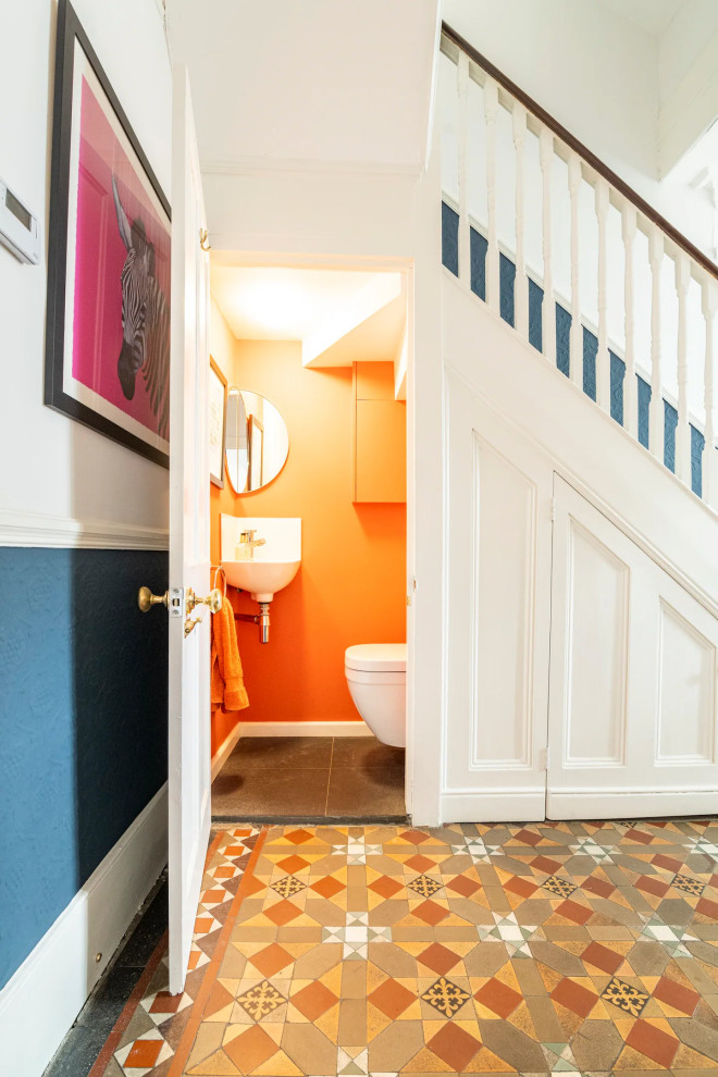 Foto di un piccolo bagno di servizio design con piastrelle bianche, pareti arancioni, pavimento in gres porcellanato, pavimento grigio e mobile bagno sospeso