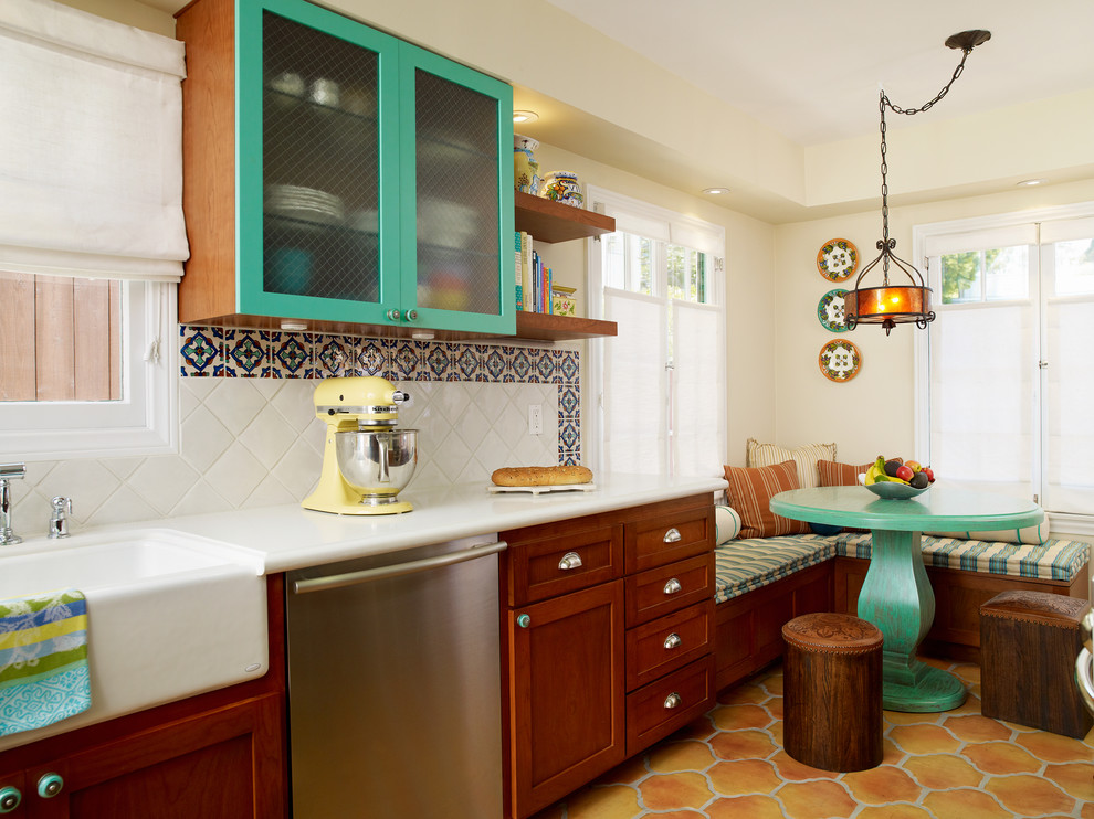 This is an example of a mediterranean eat-in kitchen in Los Angeles with glass-front cabinets, a farmhouse sink, blue cabinets, stainless steel appliances and quartz benchtops.