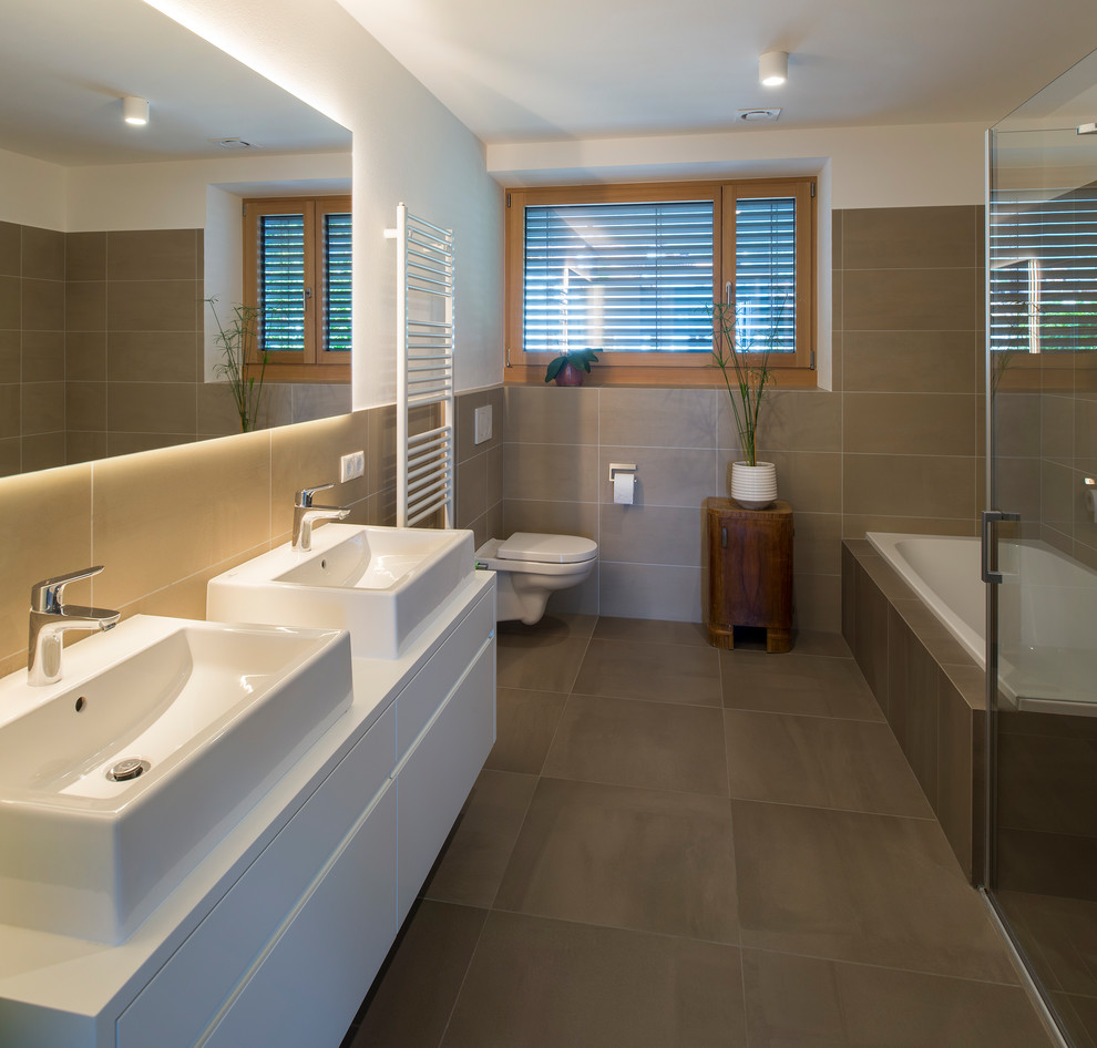 Modern master bathroom in Other with flat-panel cabinets, a drop-in tub, a corner shower, a wall-mount toilet, beige tile, white walls, a vessel sink, beige floor, a hinged shower door and white benchtops.