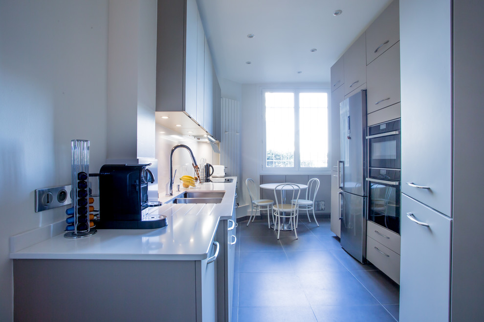 Photo of a mid-sized contemporary galley separate kitchen in Paris with an integrated sink, beaded inset cabinets, white cabinets, quartzite benchtops, white splashback, stainless steel appliances, ceramic floors, no island and grey floor.