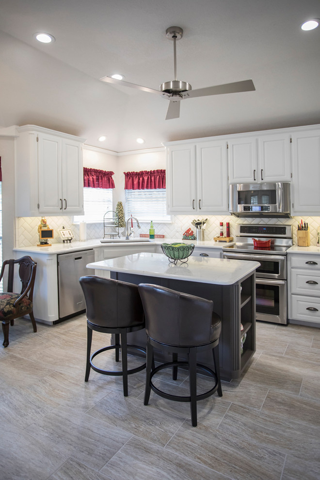 Photo of a mid-sized traditional l-shaped eat-in kitchen in Dallas with an undermount sink, raised-panel cabinets, white cabinets, quartz benchtops, white splashback, subway tile splashback, stainless steel appliances, porcelain floors, with island and grey floor.