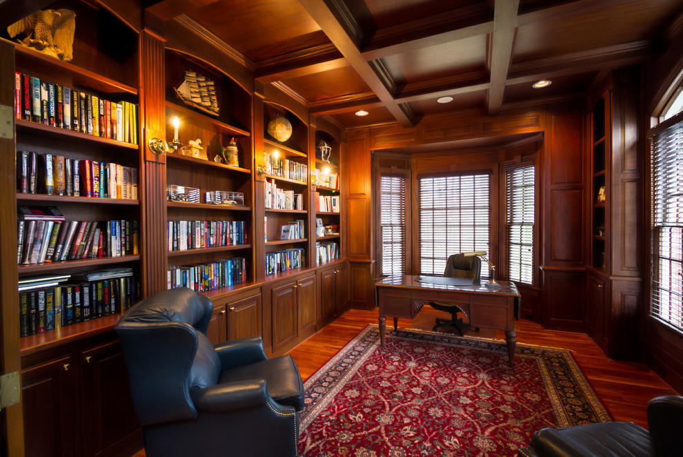 Photo of a mid-sized traditional home office in Raleigh with medium hardwood floors, no fireplace, a freestanding desk, a library and brown walls.