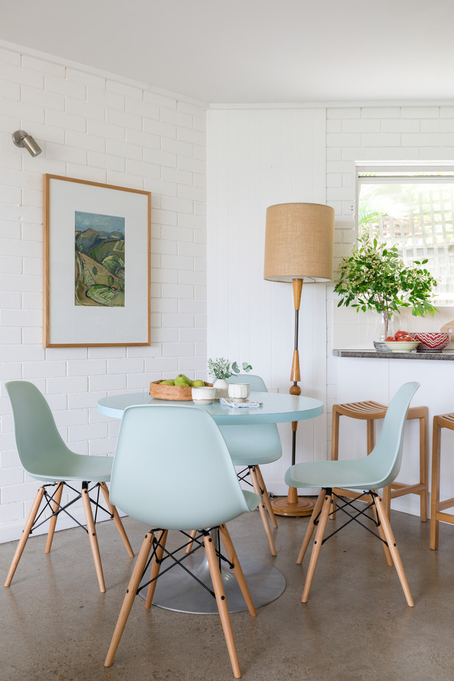 Photo of a small beach style dining room in Brisbane with white walls, concrete floors and grey floor.