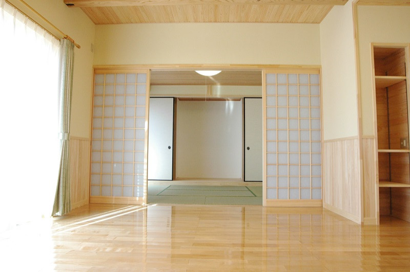 Asiatisk inredning av ett mellanstort allrum med öppen planlösning, med vita väggar, ljust trägolv, en fristående TV och beiget golv