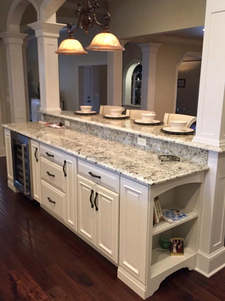 This is an example of an expansive traditional u-shaped kitchen pantry in Other with an undermount sink, raised-panel cabinets, white cabinets, granite benchtops, white splashback, stainless steel appliances and multiple islands.