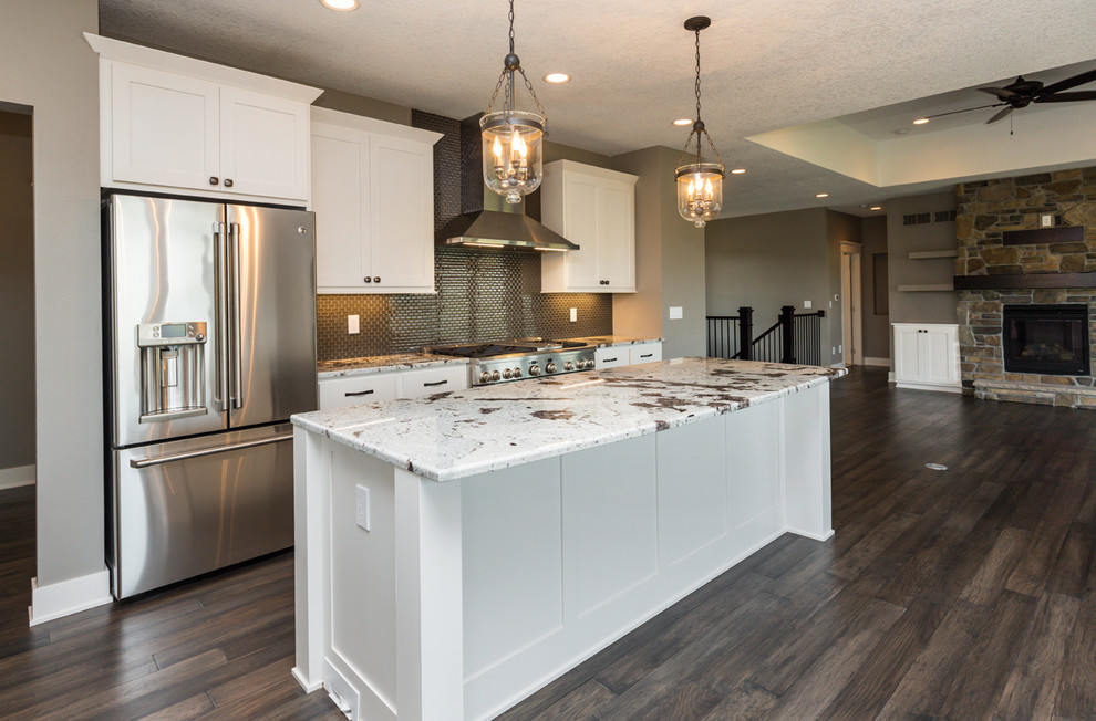 Example of a transitional l-shaped dark wood floor and brown floor kitchen design with an undermount sink, shaker cabinets, white cabinets, granite countertops, gray backsplash, glass sheet backsplash, stainless steel appliances, an island and white countertops