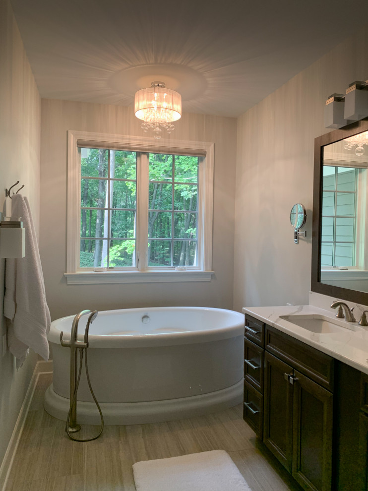 This is an example of a small beach style master bathroom in Chicago with recessed-panel cabinets, brown cabinets, a freestanding tub, beige tile and a hinged shower door.