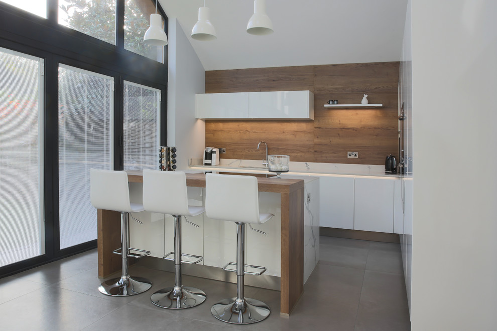 Inspiration for a small contemporary l-shaped eat-in kitchen in Essex with an integrated sink, flat-panel cabinets, white cabinets, quartzite benchtops, panelled appliances, porcelain floors and with island.