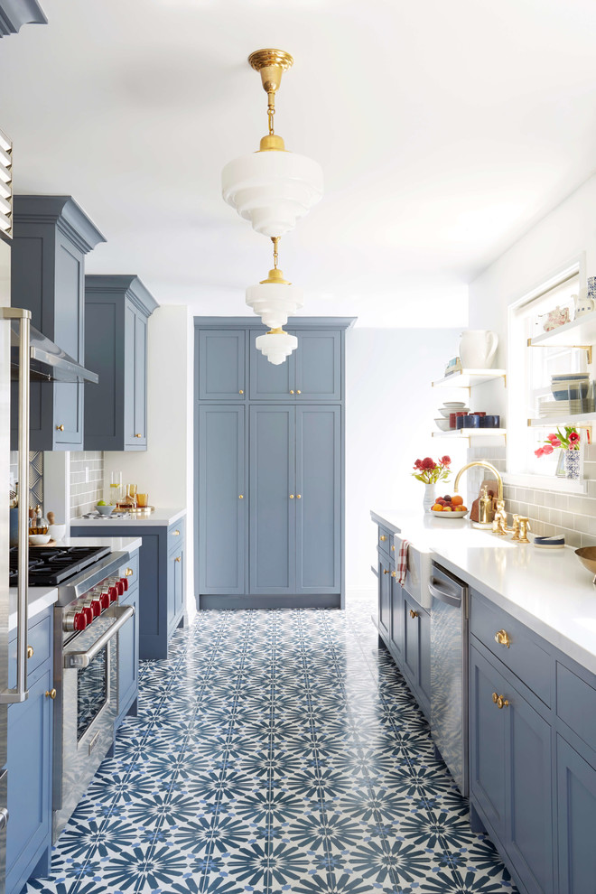 Transitional l-shaped kitchen in San Francisco with a farmhouse sink, shaker cabinets, blue cabinets, grey splashback, subway tile splashback, stainless steel appliances and multi-coloured floor.