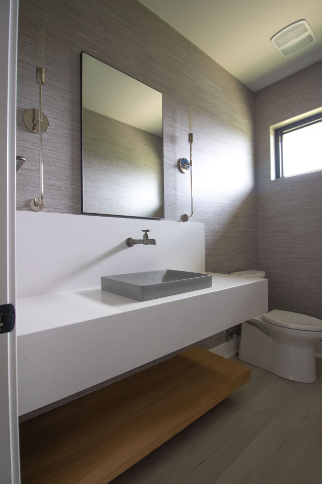 На фото: туалет в стиле неоклассика (современная классика) с унитазом-моноблоком, настольной раковиной, столешницей из искусственного кварца, белой столешницей, подвесной тумбой и обоями на стенах