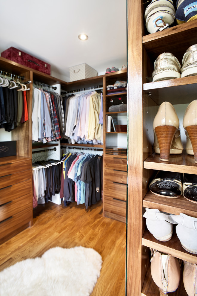 Inspiration for a large contemporary gender-neutral walk-in wardrobe in New York with light hardwood floors, flat-panel cabinets, dark wood cabinets and brown floor.