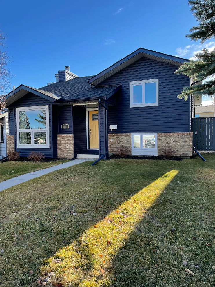 Mittelgroßes Klassisches Einfamilienhaus mit Vinylfassade und blauer Fassadenfarbe in Calgary