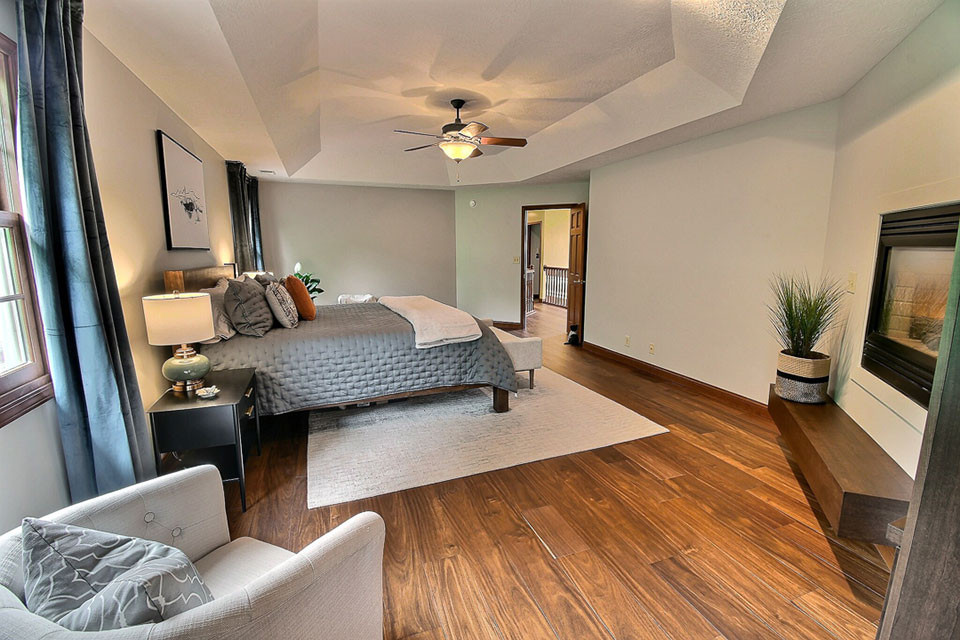 Großes Klassisches Hauptschlafzimmer mit beiger Wandfarbe, braunem Holzboden, Tunnelkamin, Kaminumrandung aus Metall und braunem Boden in Sonstige