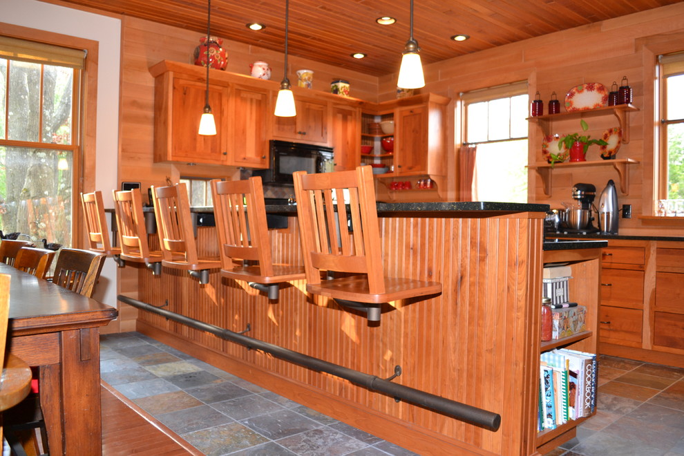 Mid-sized mountain style l-shaped dark wood floor enclosed kitchen photo with medium tone wood cabinets, black appliances and no island