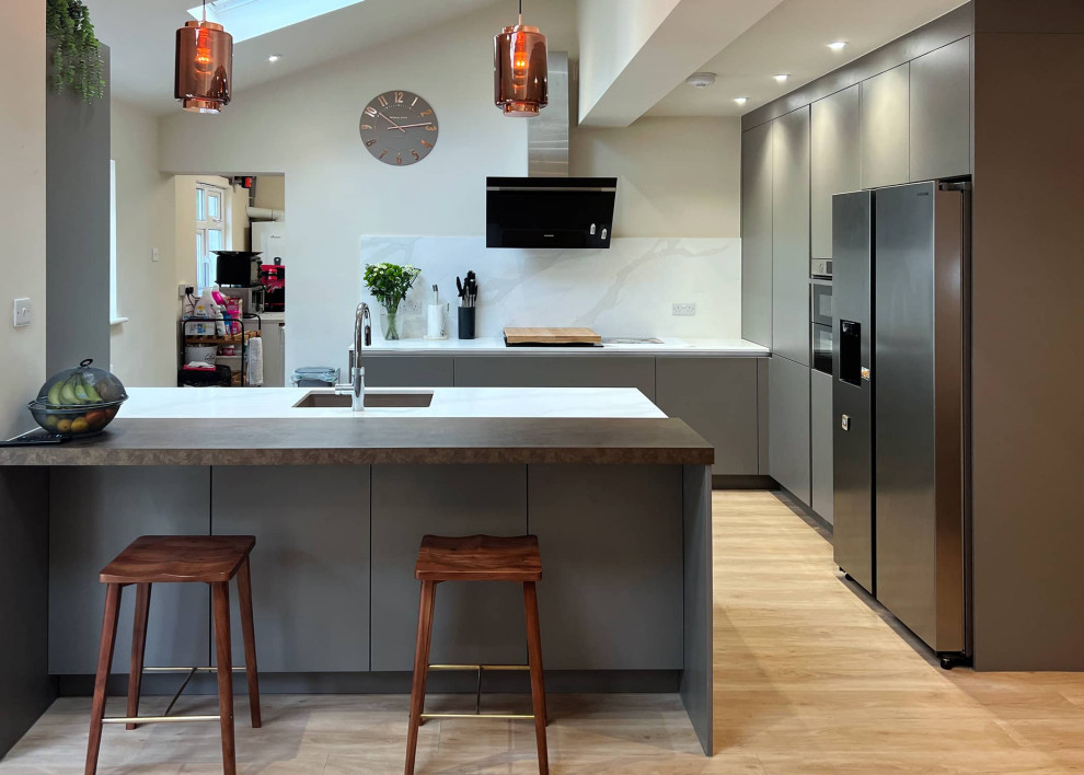 Design ideas for a medium sized contemporary grey and white l-shaped open plan kitchen in London with a single-bowl sink, flat-panel cabinets, grey cabinets, quartz worktops, white splashback, stainless steel appliances, an island, beige floors, white worktops, exposed beams and feature lighting.