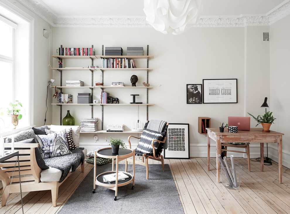 Inspiration for a mid-sized scandinavian study room in Gothenburg with white walls, light hardwood floors, no fireplace and a freestanding desk.