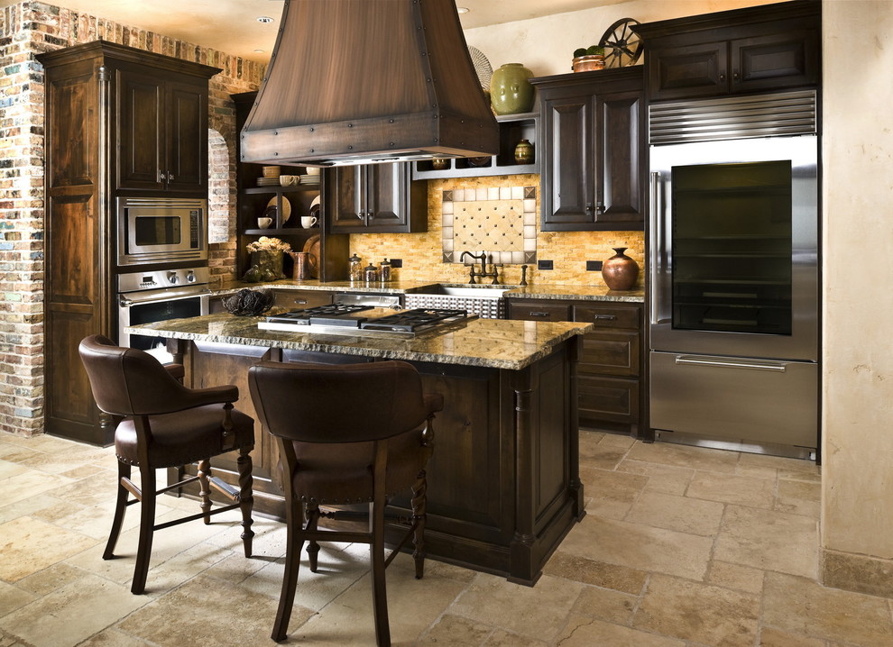 This is an example of a country kitchen in Dallas with stainless steel appliances and travertine floors.