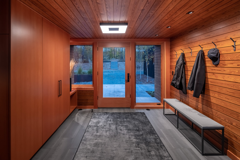 Cette image montre un hall d'entrée chalet en bois de taille moyenne avec un mur marron, un sol en carrelage de porcelaine, une porte simple, une porte en bois brun, un sol gris et un plafond en bois.