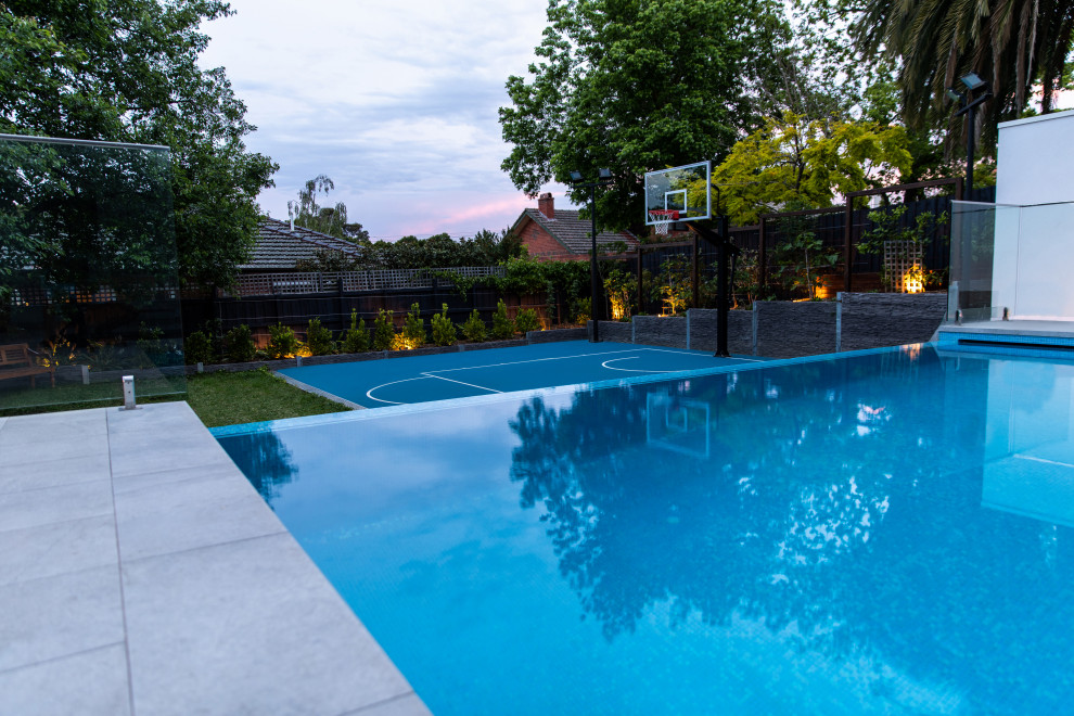 Réalisation d'un grand piscine avec aménagement paysager arrière design rectangle avec des pavés en pierre naturelle.