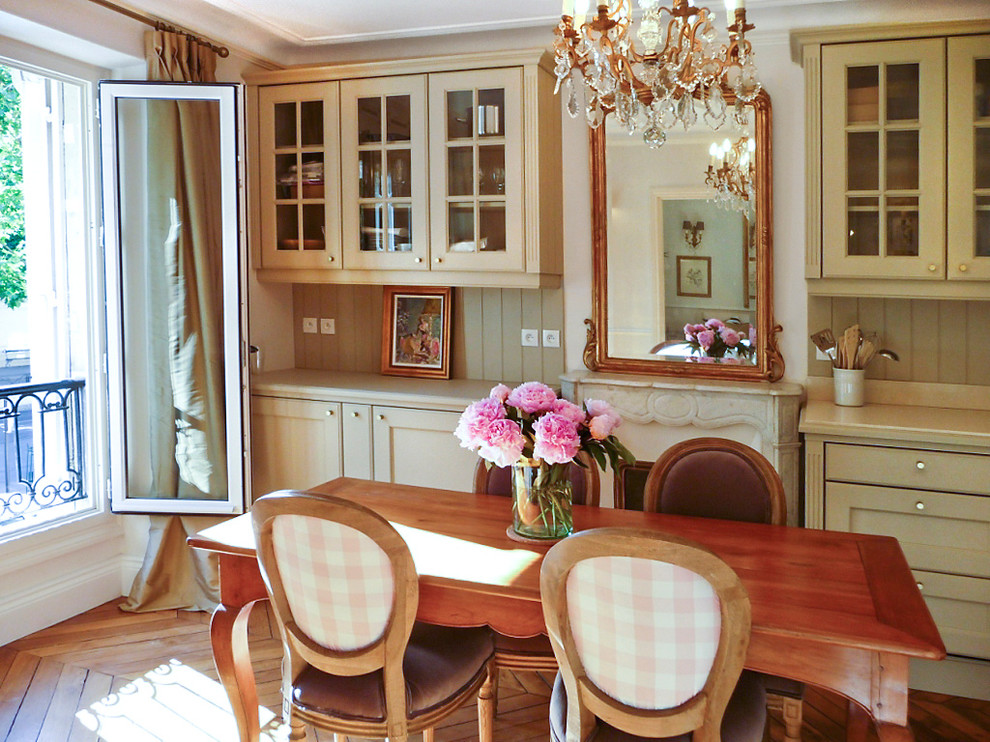 Mid-sized country kitchen/dining combo in Paris with beige walls, medium hardwood floors and a standard fireplace.