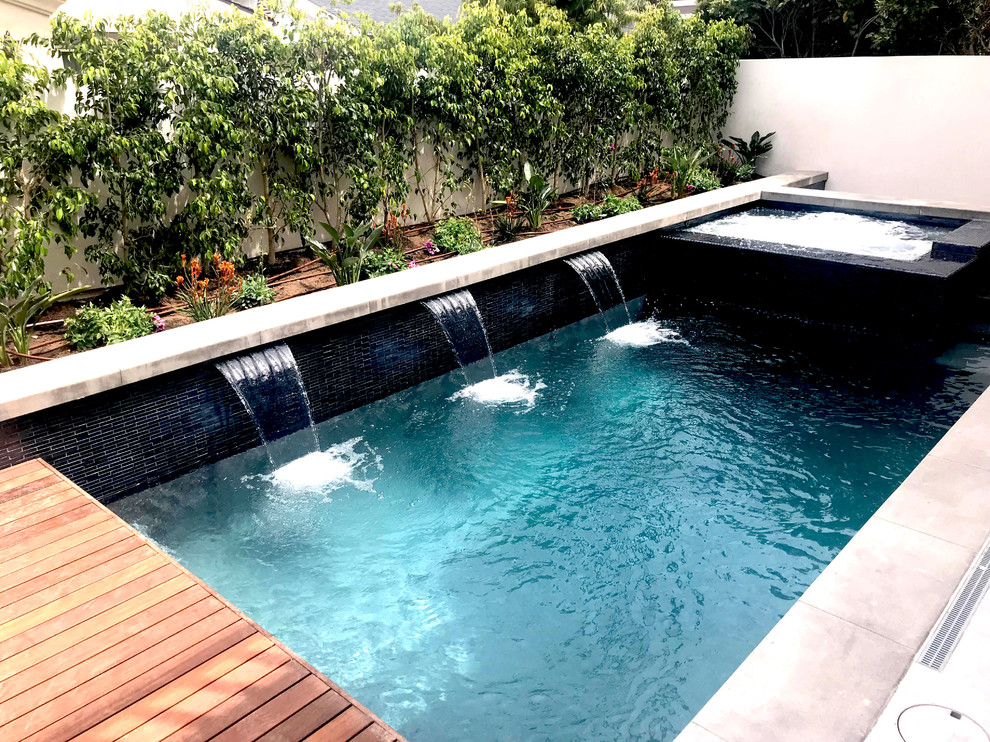 Design ideas for a small modern backyard rectangular lap pool in Los Angeles with a water feature and decking.