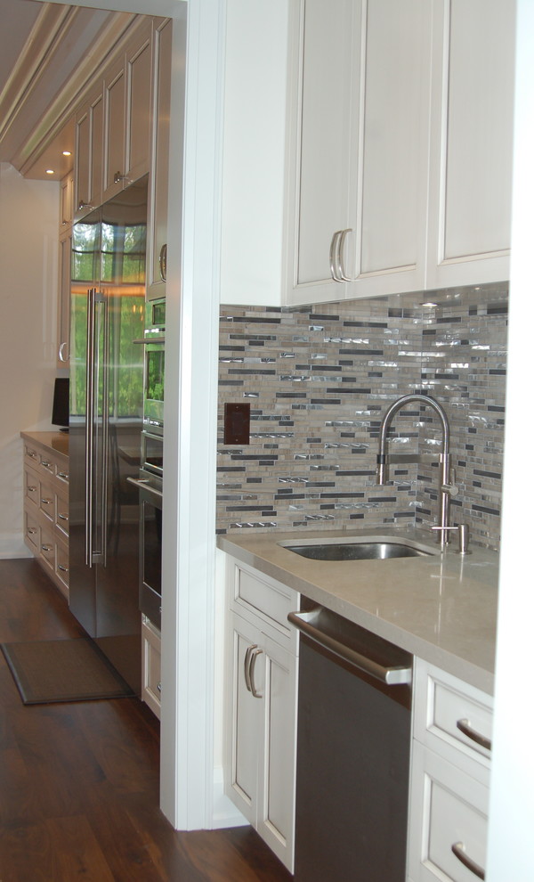 Open concept kitchen - large transitional l-shaped dark wood floor and brown floor open concept kitchen idea in Toronto with an undermount sink, beaded inset cabinets, white cabinets, quartz countertops, metallic backsplash, matchstick tile backsplash, stainless steel appliances, an island and beige countertops