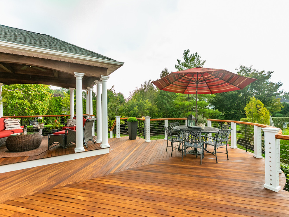 Example of a large transitional backyard deck design with a roof extension