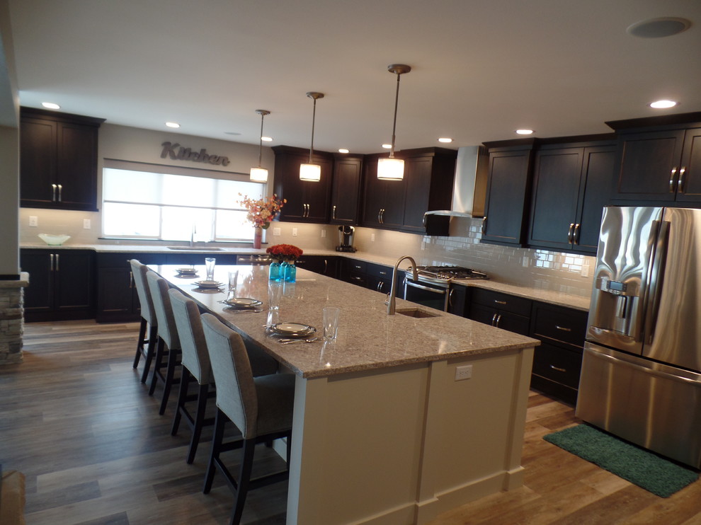 Eat-in kitchen - large transitional l-shaped medium tone wood floor and beige floor eat-in kitchen idea in Cedar Rapids with an undermount sink, shaker cabinets, dark wood cabinets, granite countertops, white backsplash, subway tile backsplash, stainless steel appliances and an island